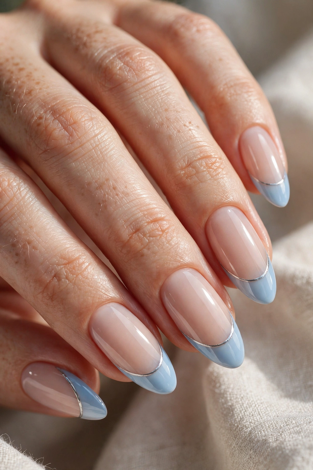 Icy blue French tip Christmas nails with silver hairline on milky base